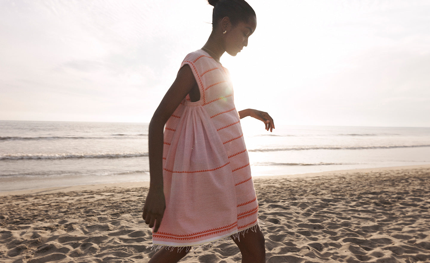 Woman Walking on the beach in Los Angeles wearing lemlem ELINA Caftan in pink color featuring orange tibeb pattern