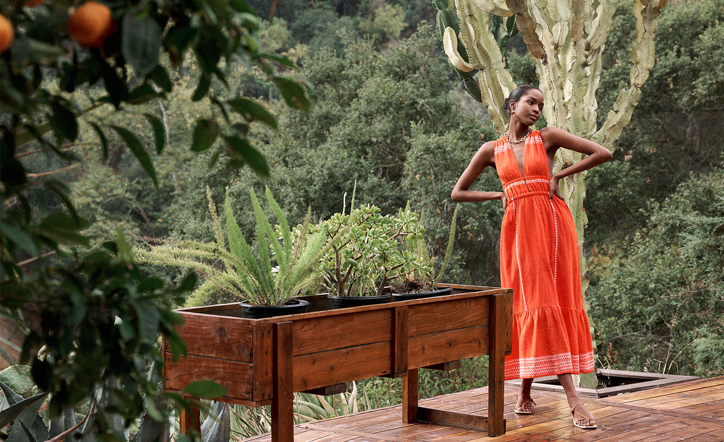 Woman Standing in the tree house wearing lemlem Lelisa Dress featuring red color and white tibeb pattern