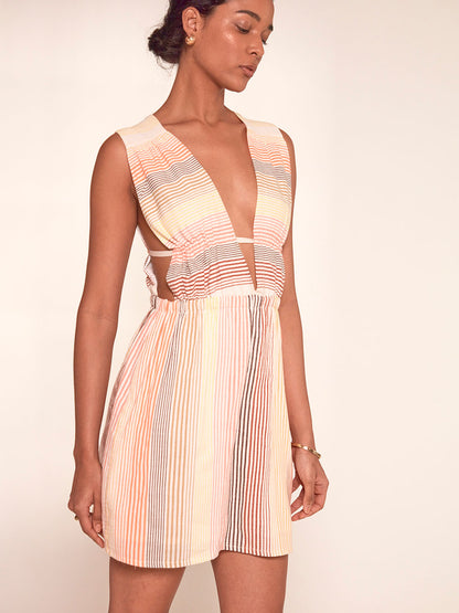 Woman Standing Wearing lemlem Anthea Dress featuring continuous stripe pattern in warm yellow, orange and peach tones