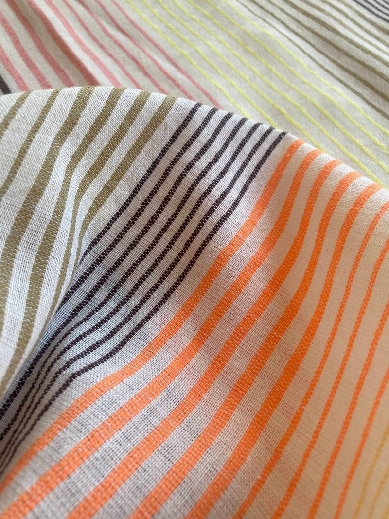 Close up on lemlem Amaresh Fabric Featuring continuous stripe pattern in warm yellow, orange and peach tones.