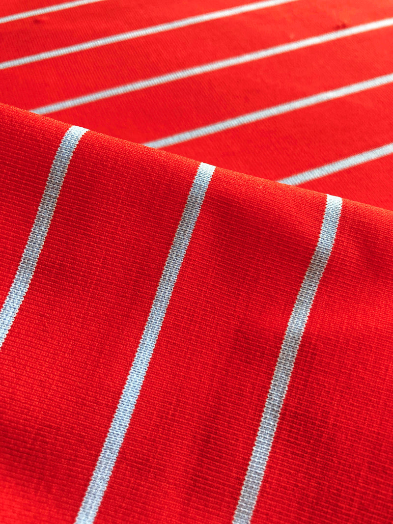 Close up on Jeliba Swim Tangerine Fabric featuring bright juicy tangerine hues accented by pale blue fine stripes
