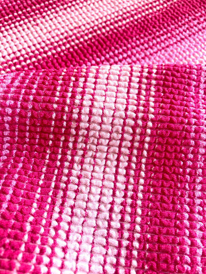 Close up on lemlem Feven Fuchsia Fabric featuring ombre design in white, soft pink, and raspberry colors