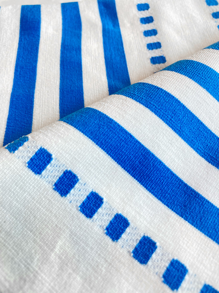 Close Up on Eshe Blue Fabric Featuring crisp white background and bright blue stripes and dots pattern and a matching brief bikini bottom
