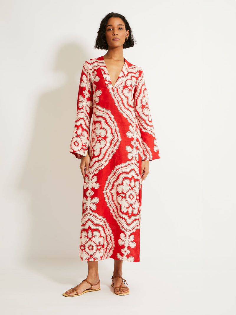 Woman Standing Wearing lemlem Theodora Dress featuring custom-designed print inspired by ancient architectural patterns in rich, vibrant red and creamy ivory colors.