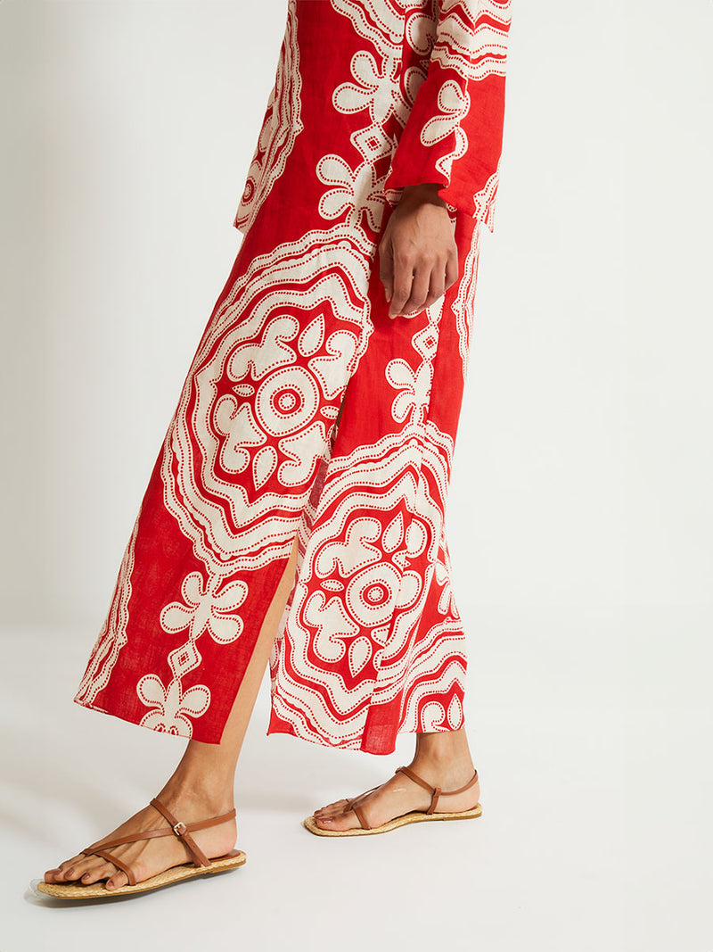 Close up on Woman's Legs Standing Wearing lemlem Theodora Dress featuring custom-designed print inspired by ancient architectural patterns in rich, vibrant red and creamy ivory colors.