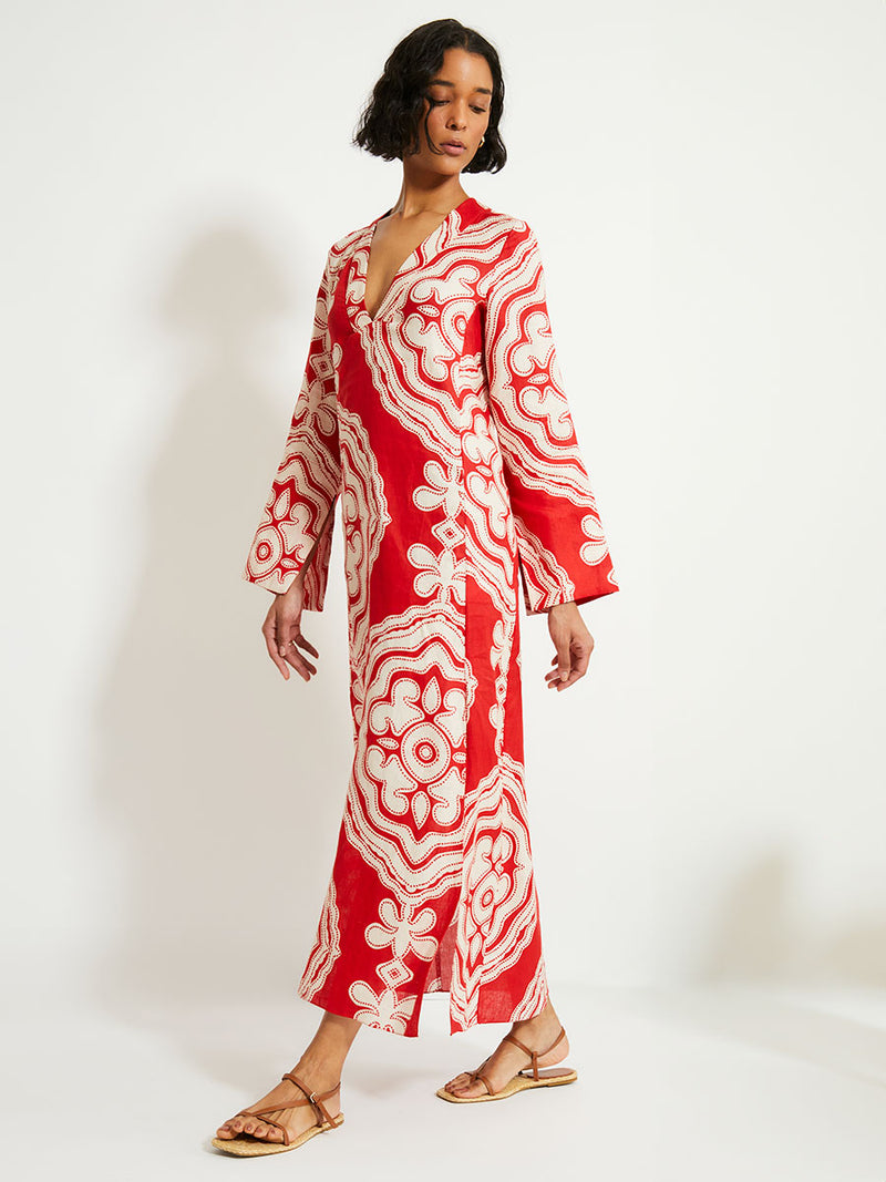 Woman Walking Wearing lemlem Theodora Dress featuring custom-designed print inspired by ancient architectural patterns in rich, vibrant red and creamy ivory colors.