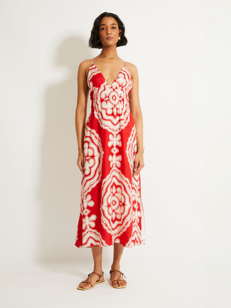 Woman Standing Wearing lemlem GETE Triangle Dress featuring custom-designed print inspired by ancient architectural patterns in rich, vibrant red and creamy ivory colors.