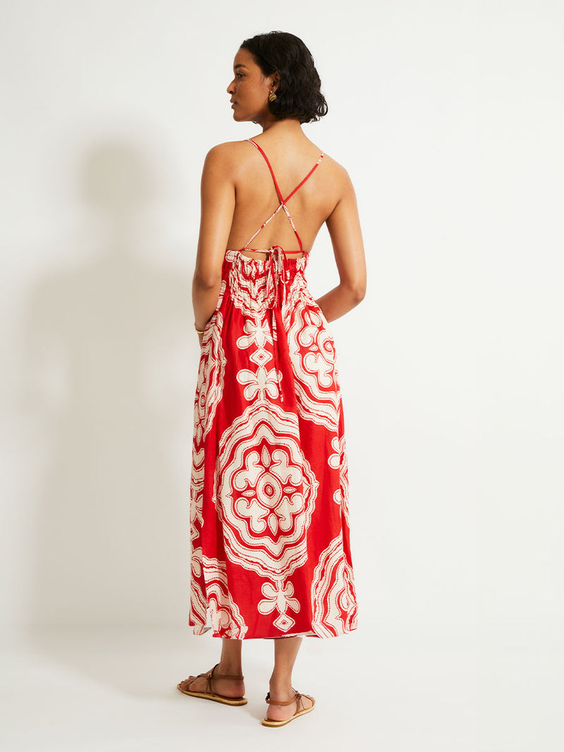 Back of a Woman Standing Wearing lemlem GETE Triangle Dress featuring custom-designed print inspired by ancient architectural patterns in rich, vibrant red and creamy ivory colors.