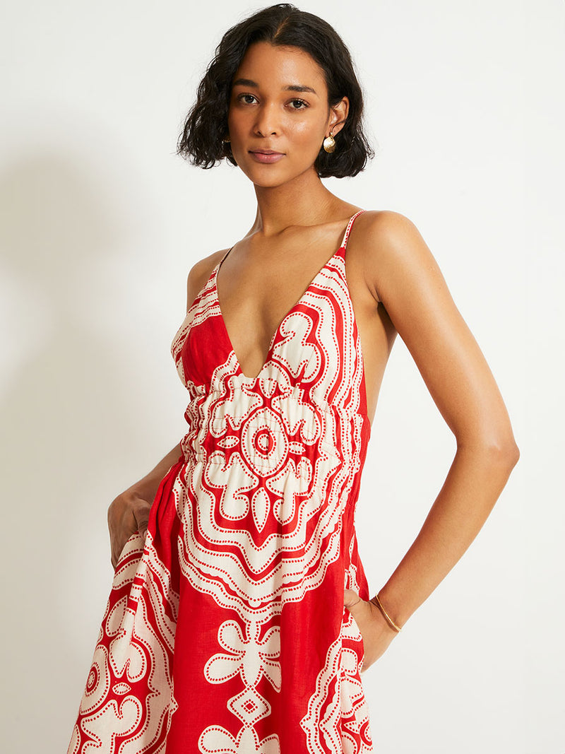 Close up om a Woman Standing Wearing lemlem GETE Triangle Dress featuring custom-designed print inspired by ancient architectural patterns in rich, vibrant red and creamy ivory colors.