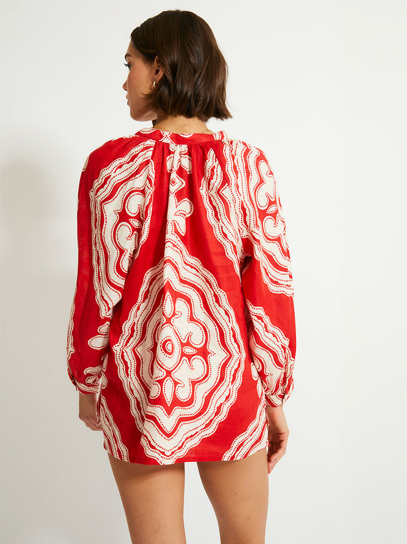 Back of a Woman Standing Wearing lemlem MITA Blouse featuring custom-designed print inspired by ancient architectural patterns in rich, vibrant red and creamy ivory colors.