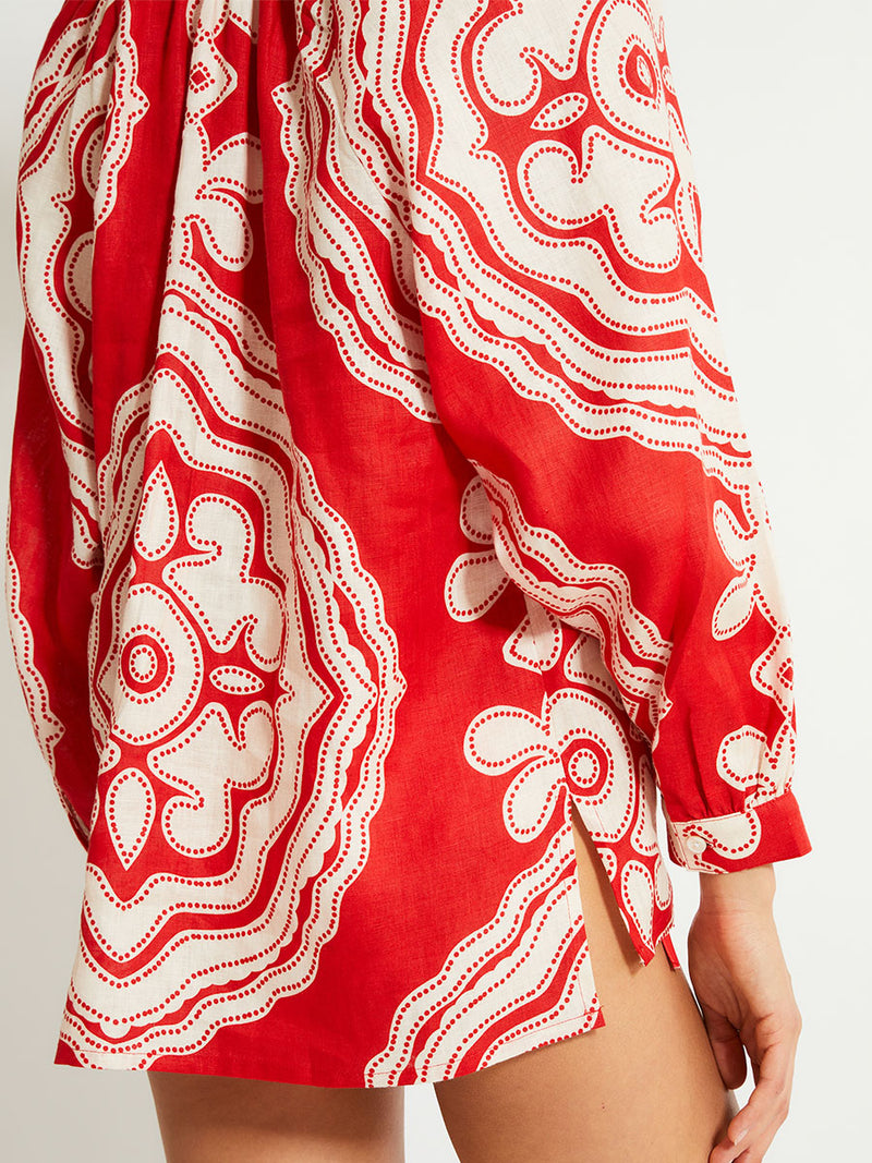 Close up on a Woman's Back Standing Wearing lemlem MITA Blouse featuring custom-designed print inspired by ancient architectural patterns in rich, vibrant red and creamy ivory colors.