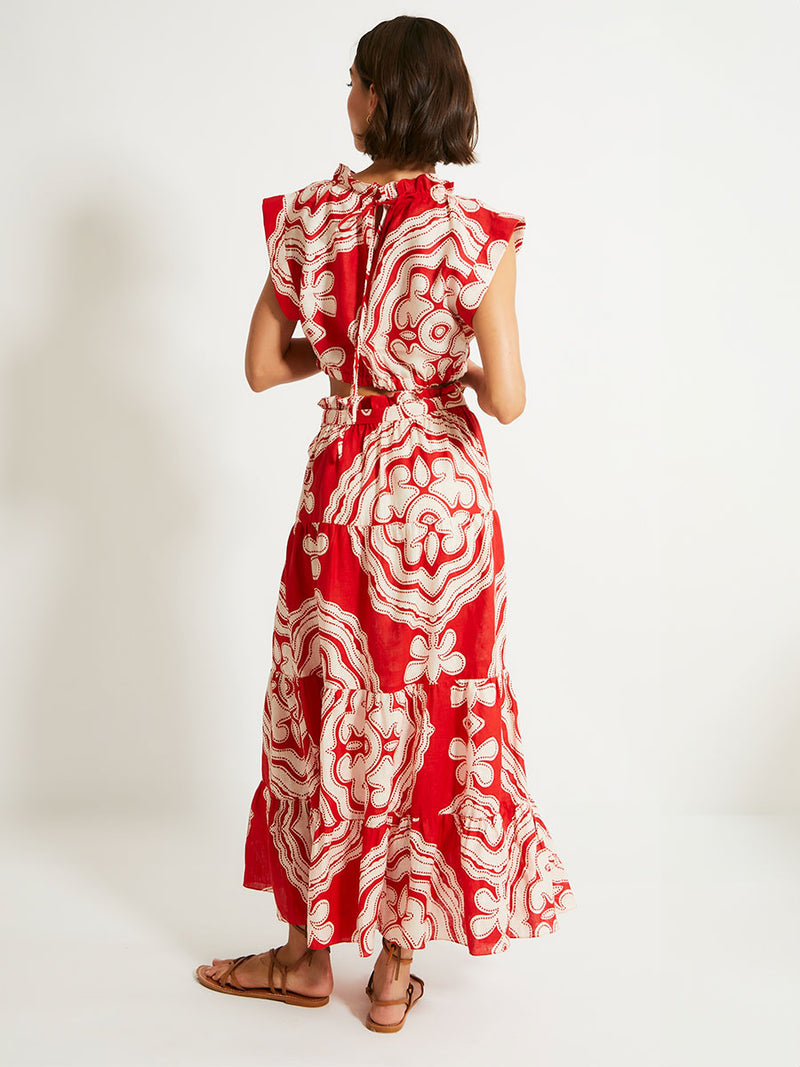 Back of a Woman Standing Wearing lemlem MUNA Crop Top and SANA Skirt featuring custom-designed print inspired by ancient architectural patterns in rich, vibrant red and creamy ivory colors.