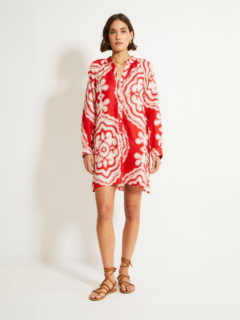 Woman Standing Wearing lemlem MEAZA Button Up Dress featuring custom-designed print inspired by ancient architectural patterns in rich, vibrant red and creamy ivory colors.