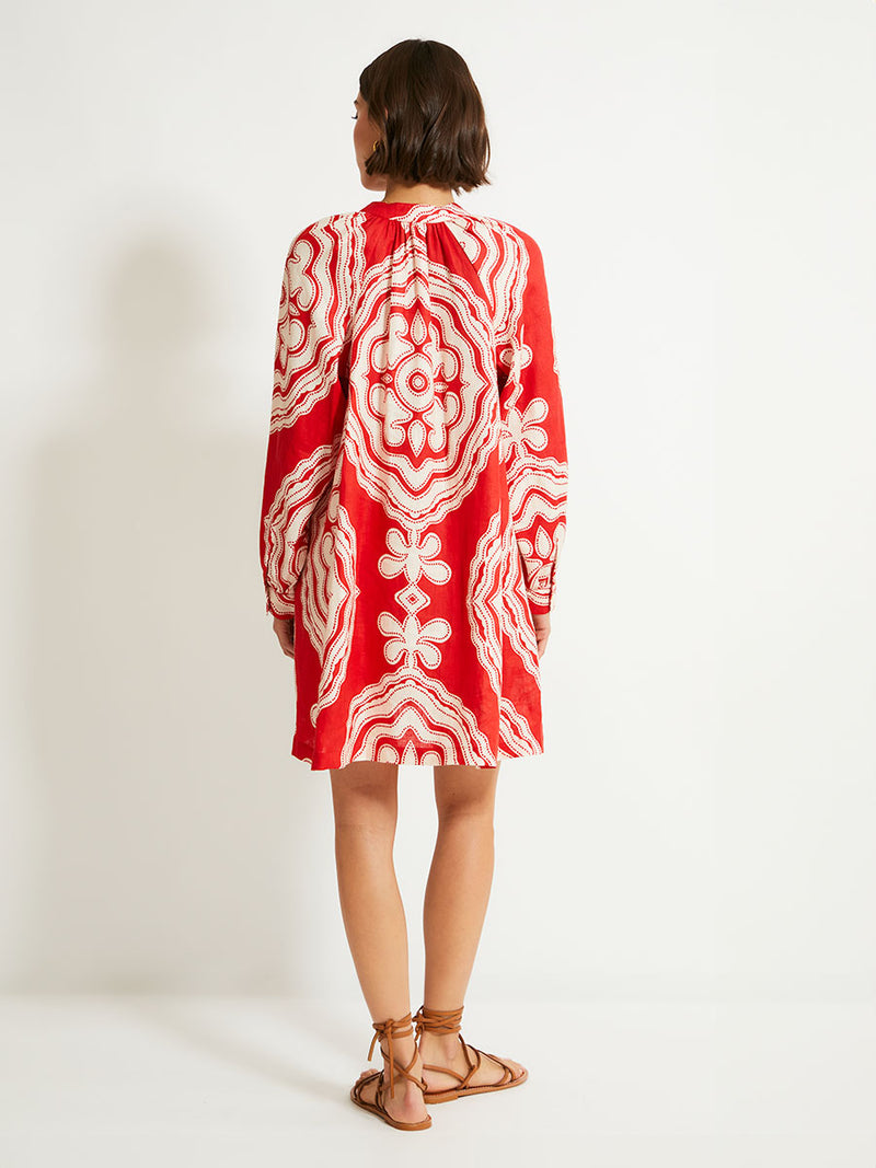 Back of a Woman Standing Wearing lemlem MEAZA Button Up Dress featuring custom-designed print inspired by ancient architectural patterns in rich, vibrant red and creamy ivory colors.