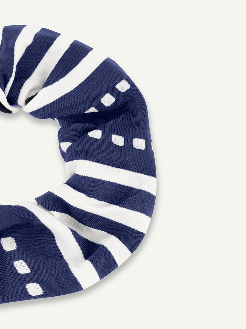 Close up on lemlem scrunchie featuring white stripes and graphic linesand holding a pouch featuring white tibeb pattern in white color on navy background