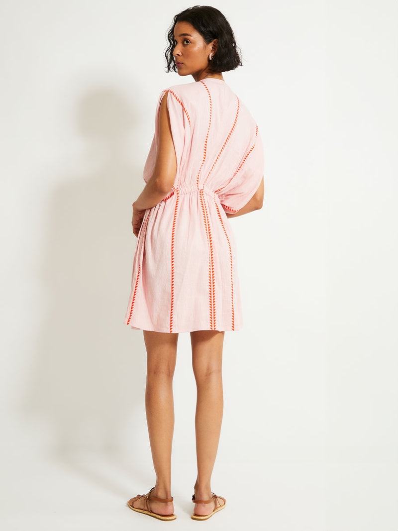 Back of a Woman Standing Wearing lemlem ALEM Plunge Dress  featuring vibrant orange red Tibeb pattern on a soft antique rose pink background, with a hint of citron tipping.