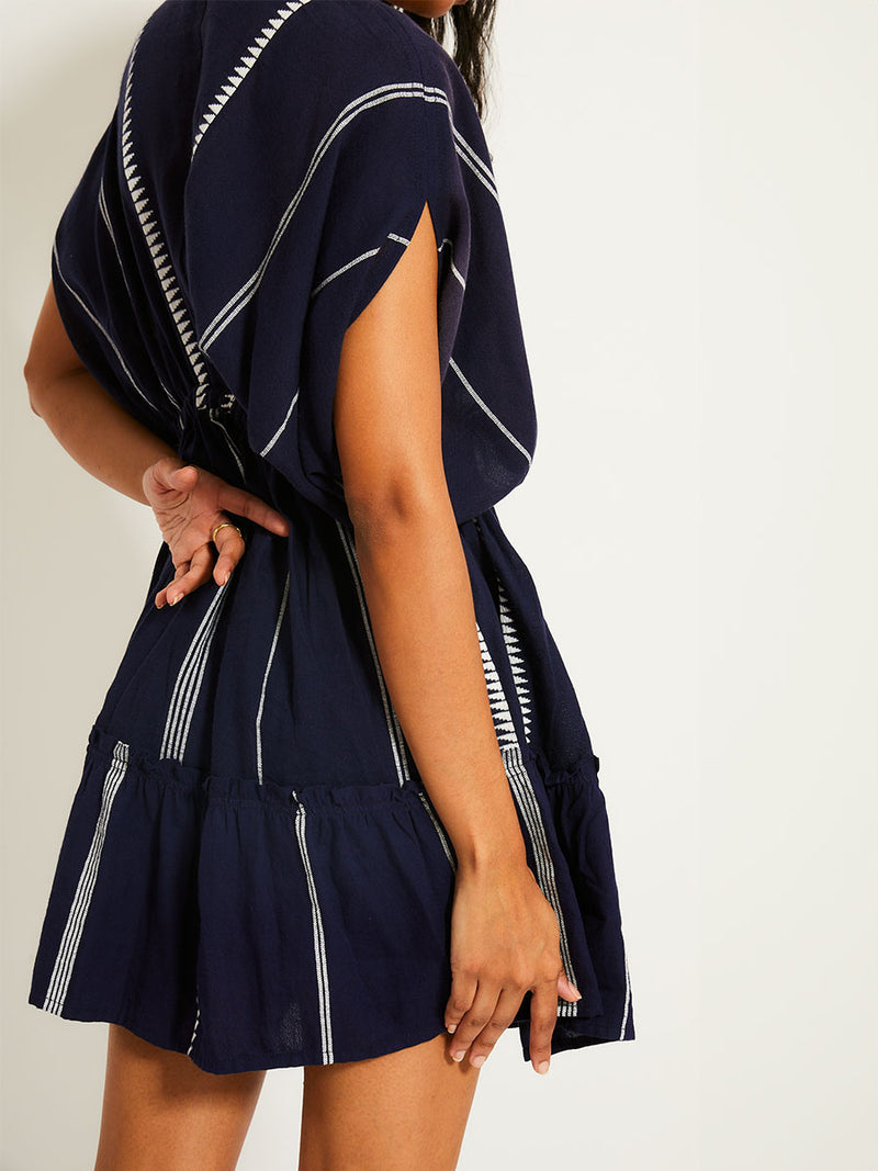 Side view of the back of a woman wearing the Nunu short Plunge Neck in Navy blue with white stripes and graphic lines.