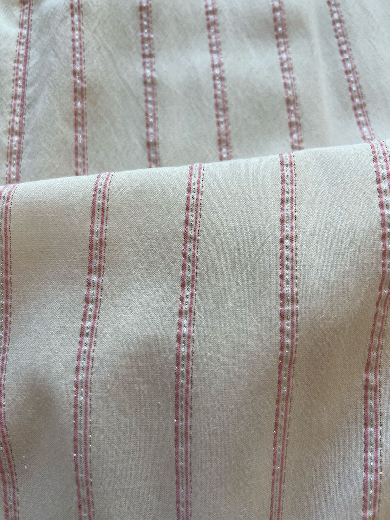 close up on lemlem aweke ivory fabric featuring feminine, classic stripe pattern in soft pink on a cream background with a touch of shine.