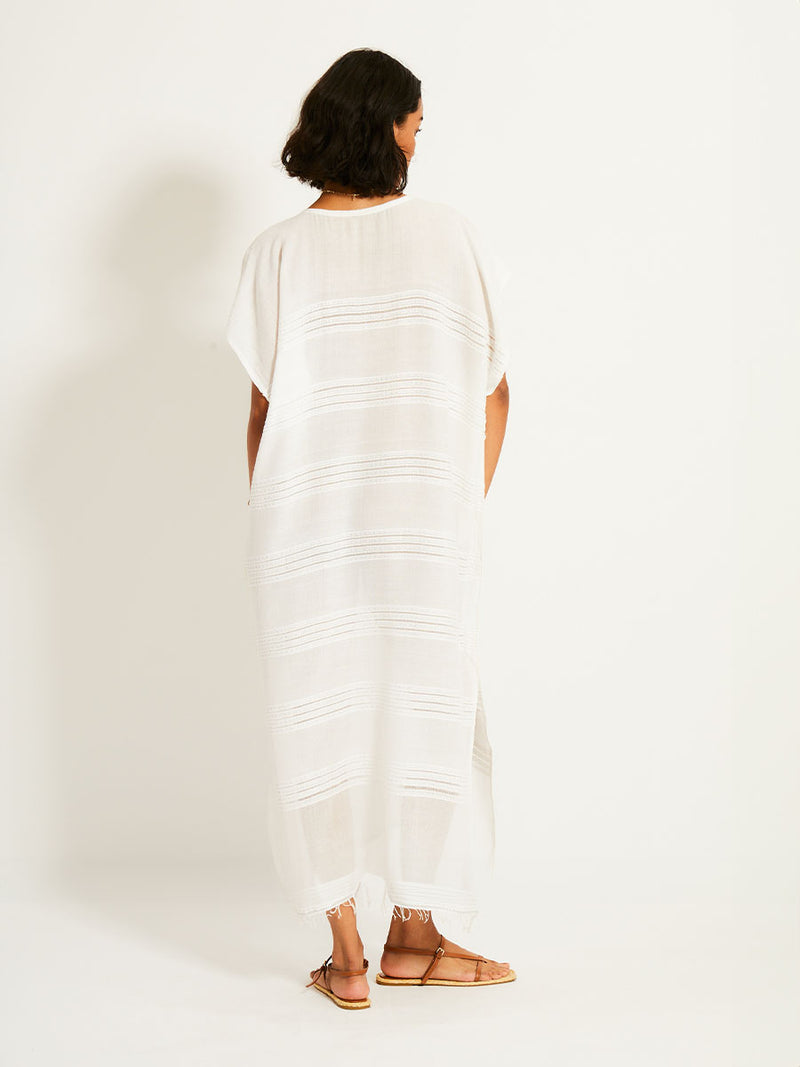 Back view of woman standing wearing a white Abira classic caftan with stitches of silver lurex