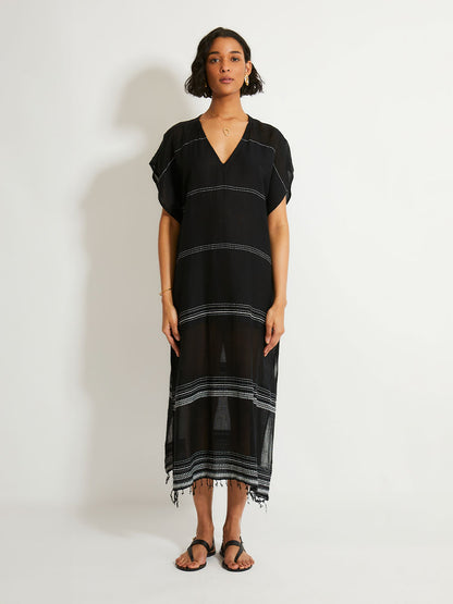 Woman standing wearing the Leliti Classic Caftan in Black with white stitching allover.