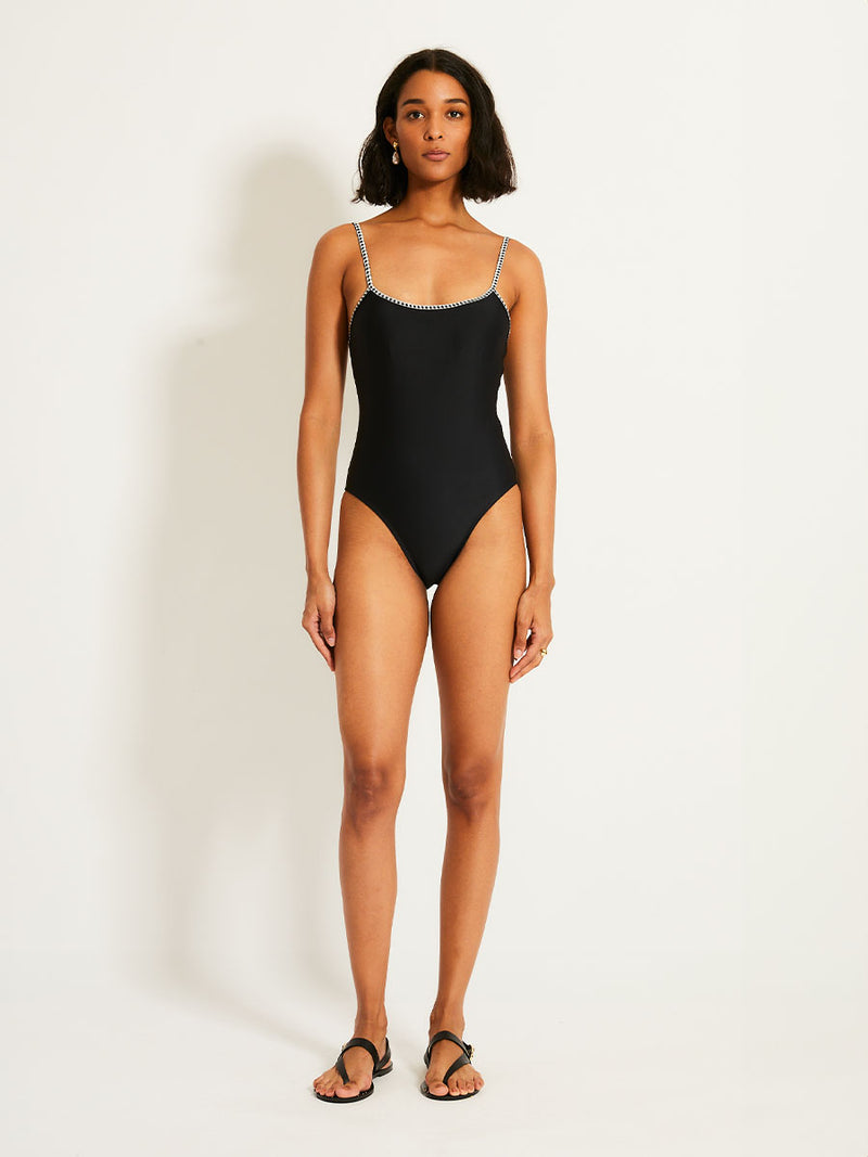 Woman standing wearing the Lena Classic One Piece in Black featuring a black and white tibeb trim.