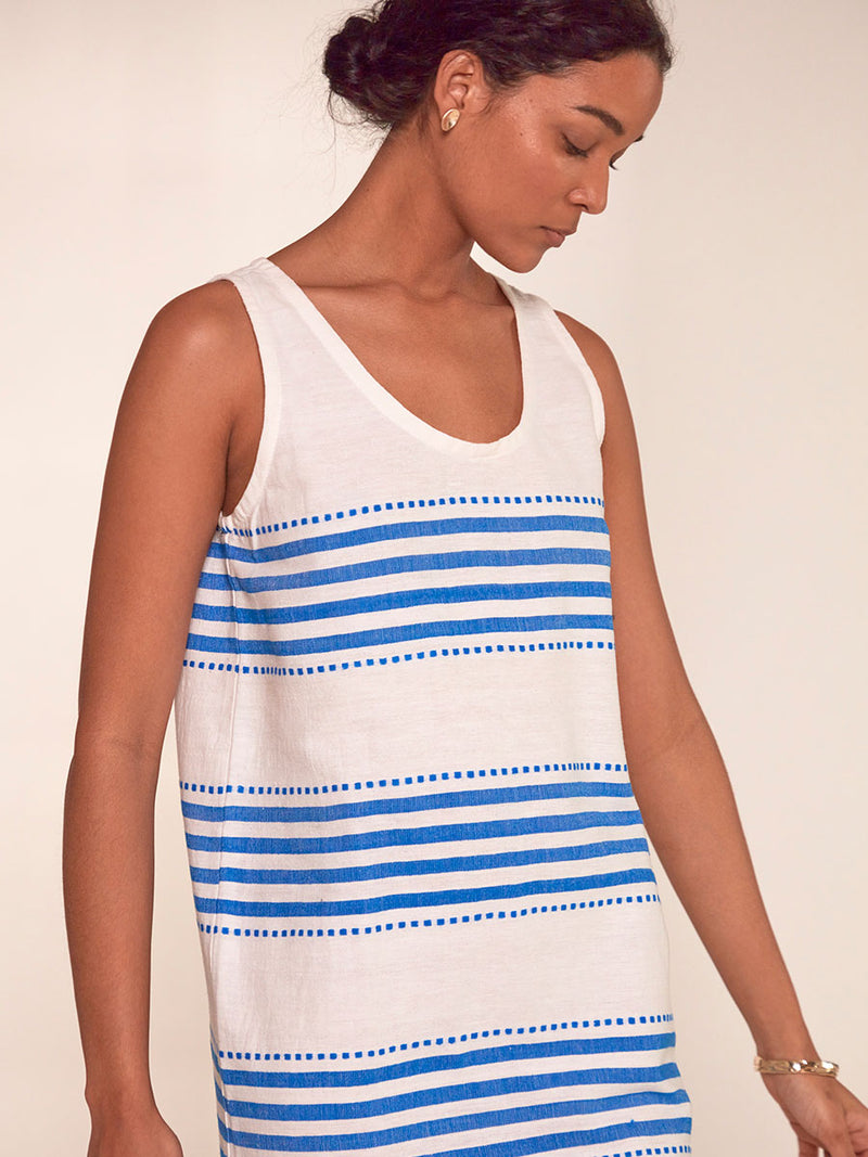 Close up on a Woman Standing Wearing lemlem Lilian Tank Dress Featuring crisp white background and bright blue stripes and dots pattern