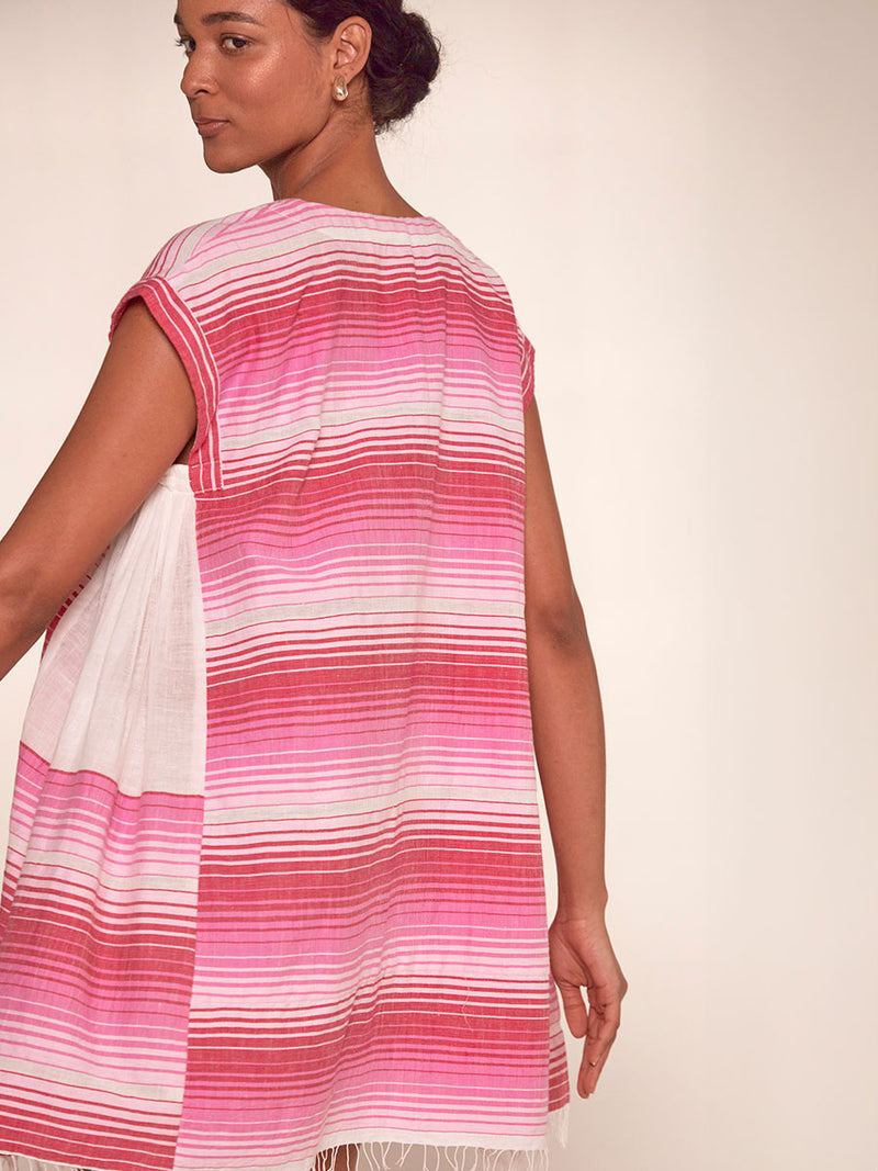 Back View of a Woman Standing Wearing emlem Elina Caftan Dress featuring white, soft pink, and raspberry stripes that effortlessly blend into a stunning ombre effect