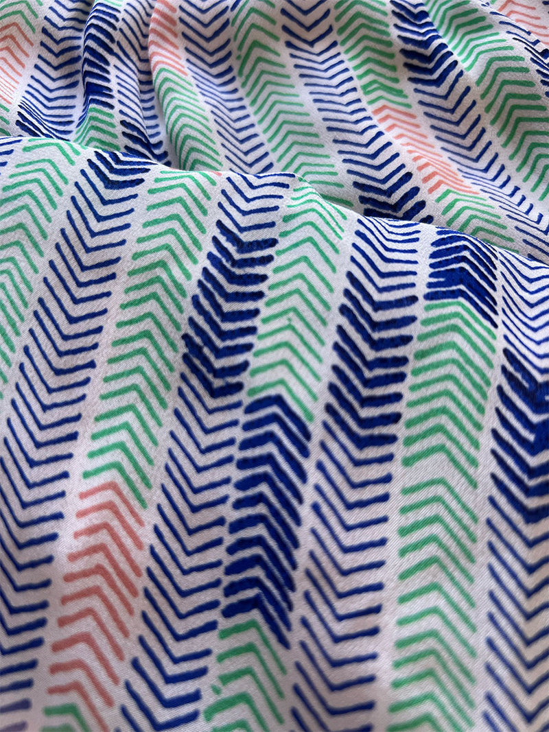 close up on lemlem gigi azure fabric featuting cool shades of blue, green, and coral, inspired by African geometric chevron patterns.