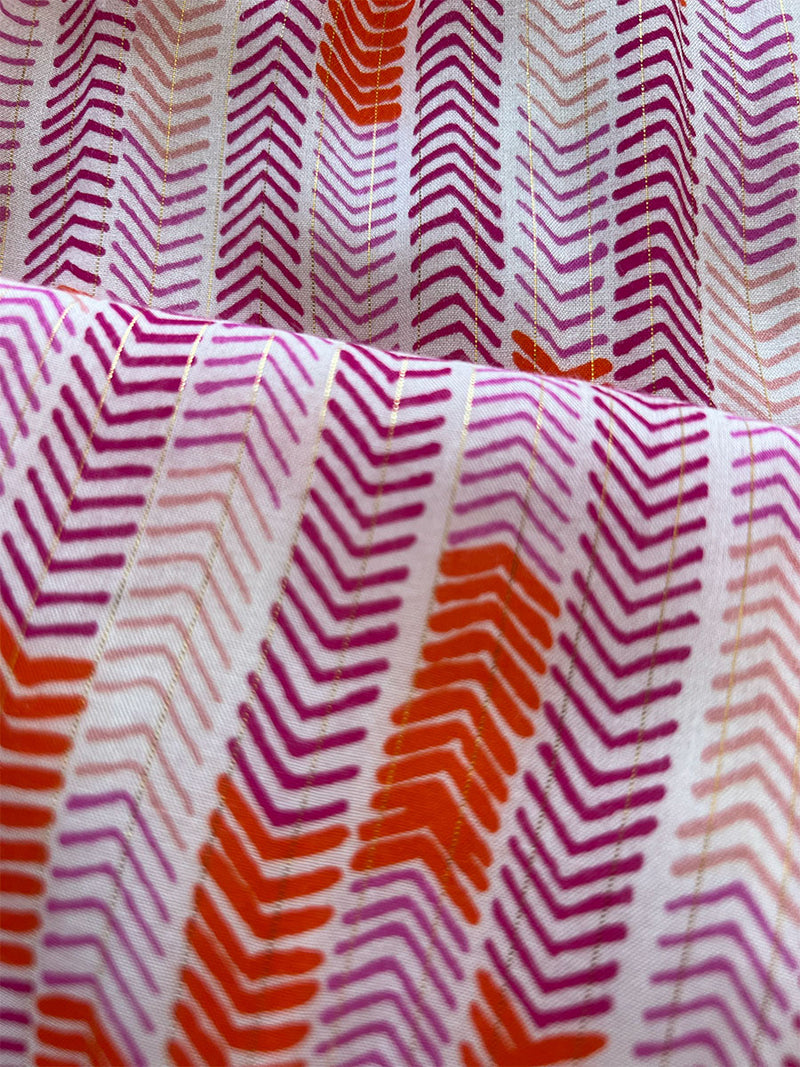 close up on lemlem gigi pink fabric featuring featuring pink, peach and orange allover chevron print and strips of gold lurex.