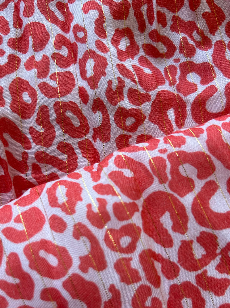 close up on lemlem halima red fabric featruring lemlem signature leopard print in a gorgeous soft coral pink red