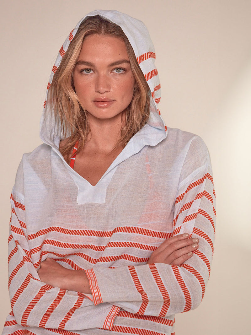 Close up on a Woman Standing Wearing lemlem Henok Hoodie featuring playful pattern of red dots becoming stripes on a pale blue background and a matching safia shorts