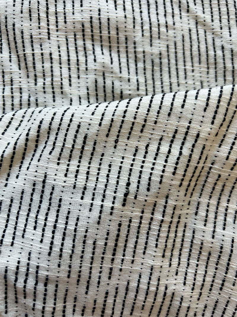 close up on lemlem imani black fabric featuring chic, geometric pattern with vertical dashes arranged in a dynamic chevron style, adding a touch of modern sophistication.