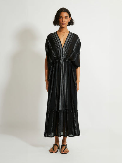 woman standing wearing the Leliti Plunge Neck Dress in Black with white stitching allover.