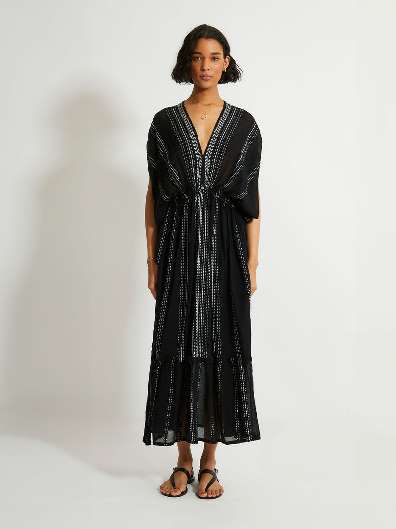 woman standing wearing the Leliti Plunge Neck Dress in Black with white stitching allover.