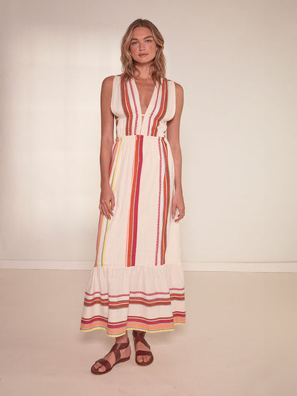 Woman standing wearing lemlem Lelisa V Neck Dress featuring tibeb inspired stripes in a vibrant fiesta of colors against a creamy vanilla background.