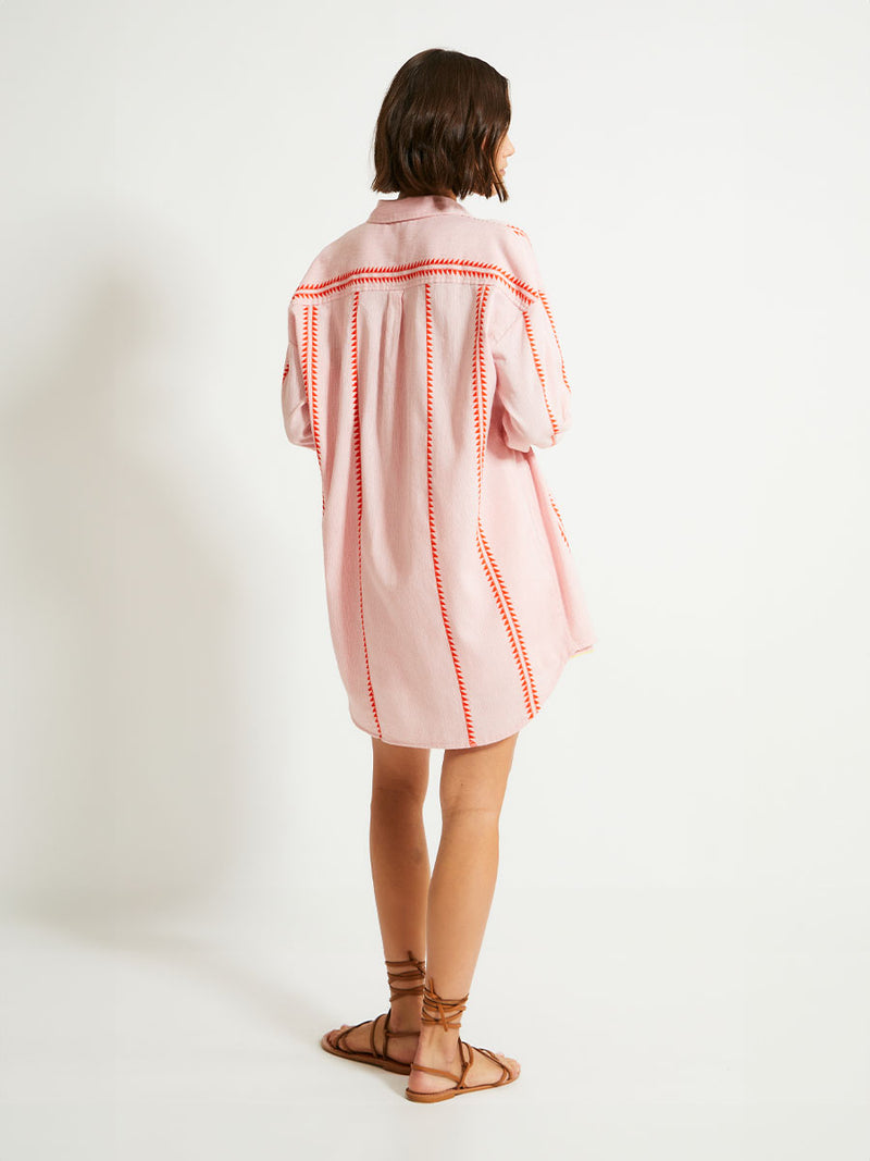 Back of a Woman Standing Wearing lemlem MARIAM Shirt  featuring vibrant orange red Tibeb pattern on a soft antique rose pink background, with a hint of citron tipping and matching shorts