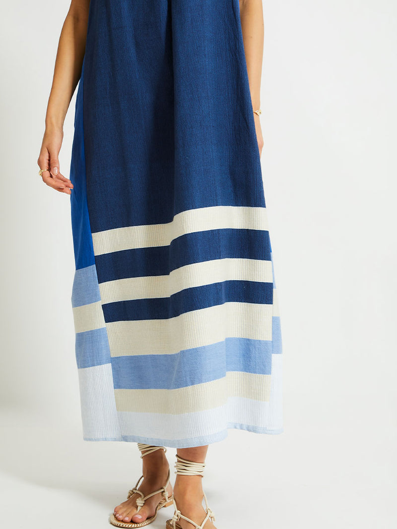 Close up on Woman's Legs Standing Wearing lemlem NIA Slip Dress featuring a striking color-block combination of three shades of blue, paired with bands of neutral cream and white