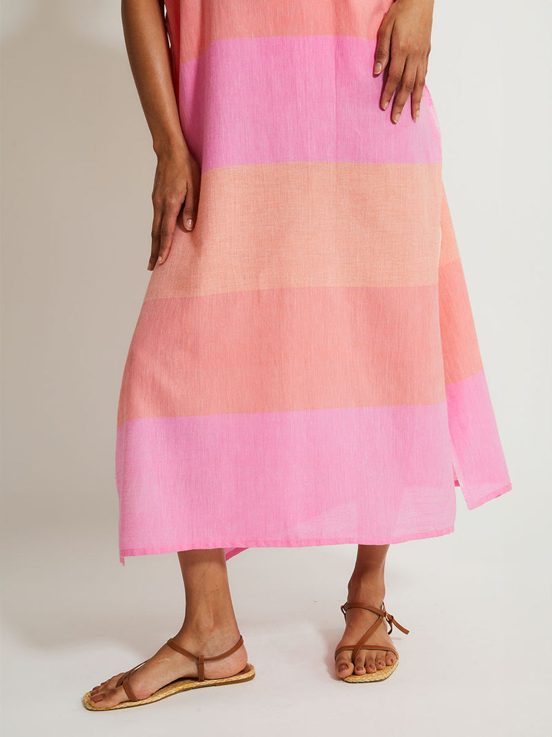 Close up on Woman's legs Standing Wearing lemlem DALILA Caftan featuring gauzy fabric with a beautiful ombre color block of pink, blush, and peach colors.