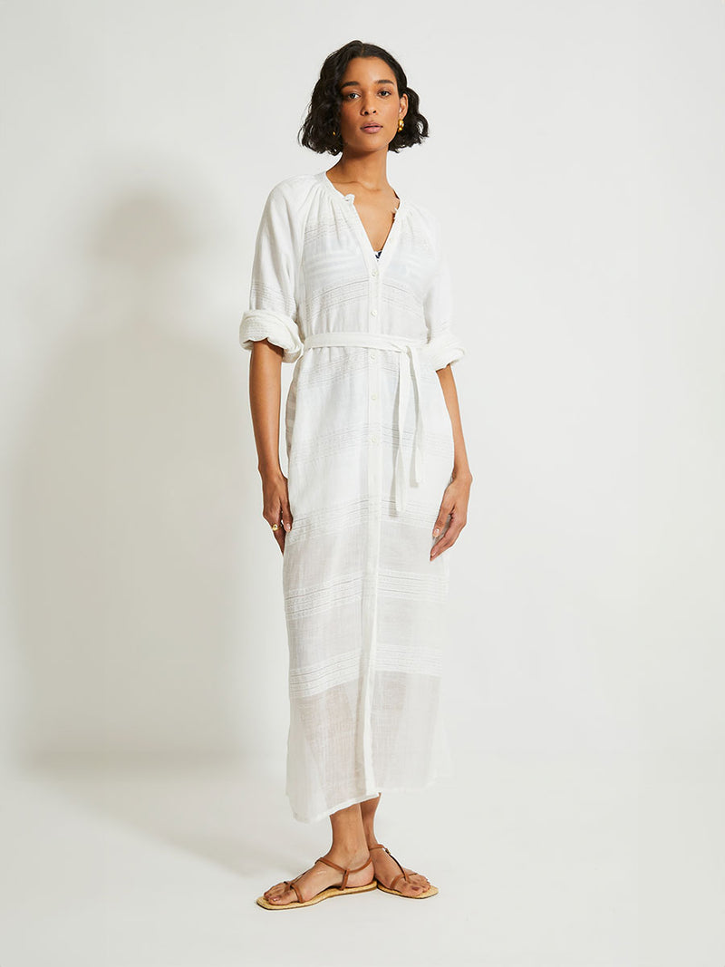 Woman Standing wearing lemlem Makeda Dress featuring  textured solid and sheer weaving highlighted by delicate shimmering silver dots on a bright white background