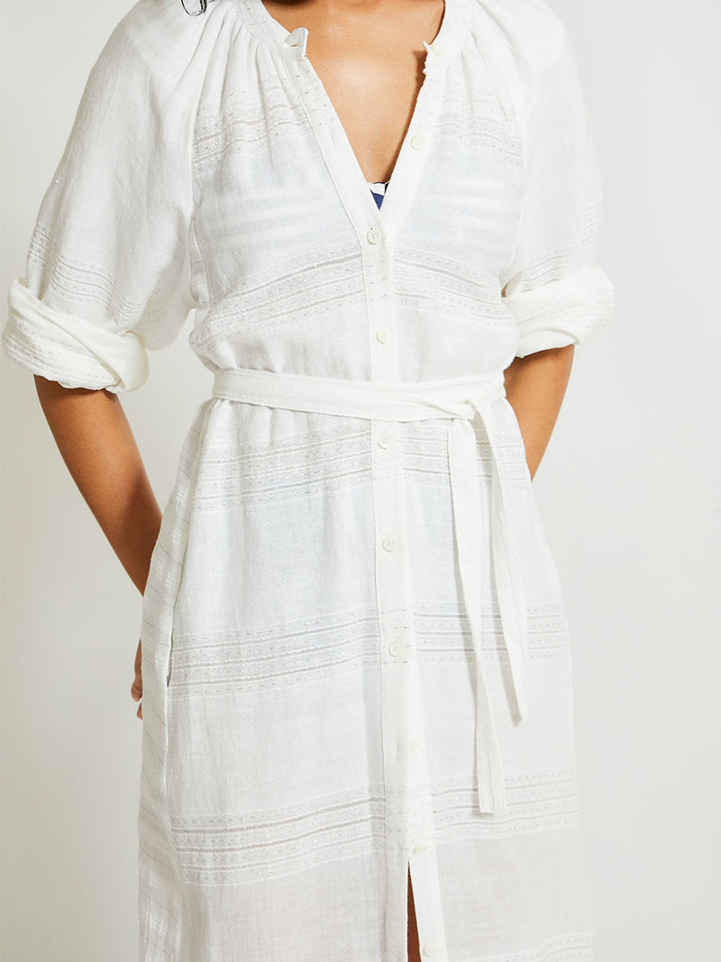 Close up on a Woman Standing wearing lemlem Makeda Dress featuring  textured solid and sheer weaving highlighted by delicate shimmering silver dots on a bright white background