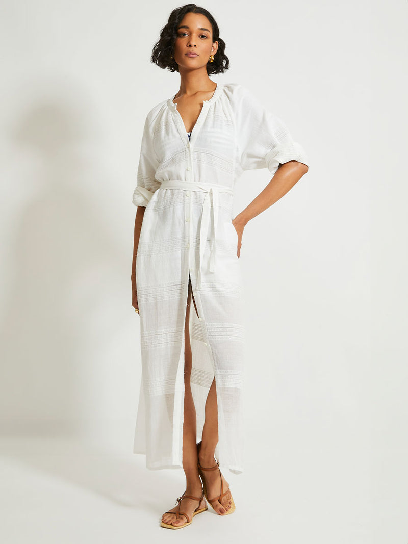 Woman Standing wearing lemlem Makeda Dress featuring  textured solid and sheer weaving highlighted by delicate shimmering silver dots on a bright white background