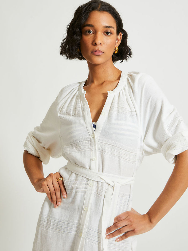 Close up on a Woman Standing wearing lemlem Makeda Dress featuring  textured solid and sheer weaving highlighted by delicate shimmering silver dots on a bright white background