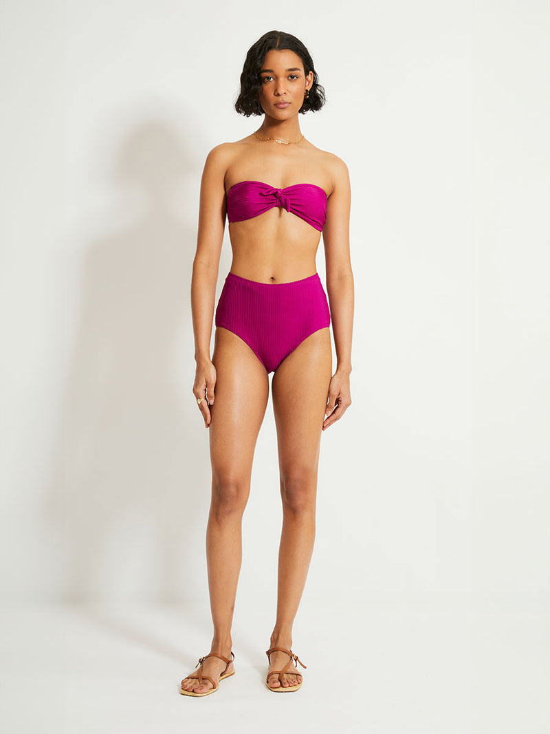 Woman Standing Wearing lemlem AVA Bandeau Top featuring  rich, opulent berry color and a matching bikini bottom