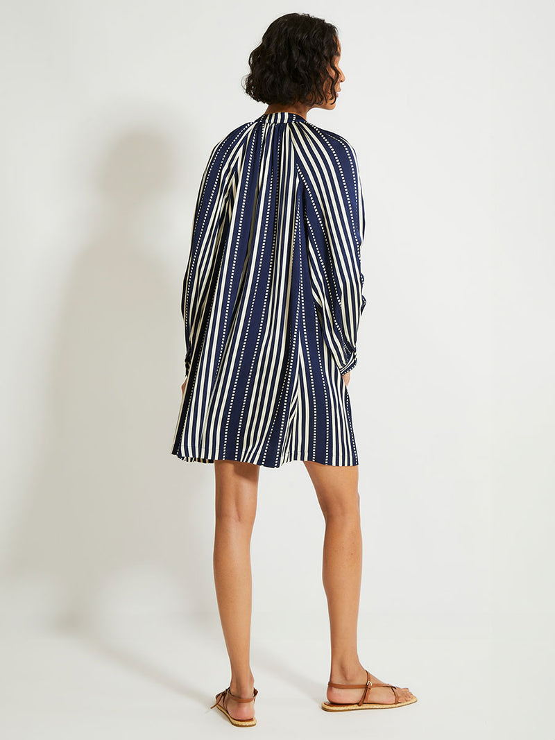 Back of a Woman Standing Wearing lemlem Meaza dress featuring a classic navy background with ivory stripes and dots