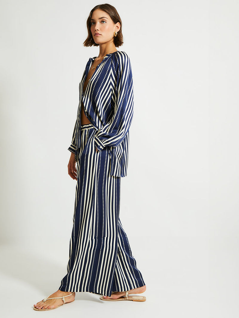 Side Shot of a Woman Standing Wearing lemlem Desta Pants featuring a classic navy background with ivory stripes and dots 