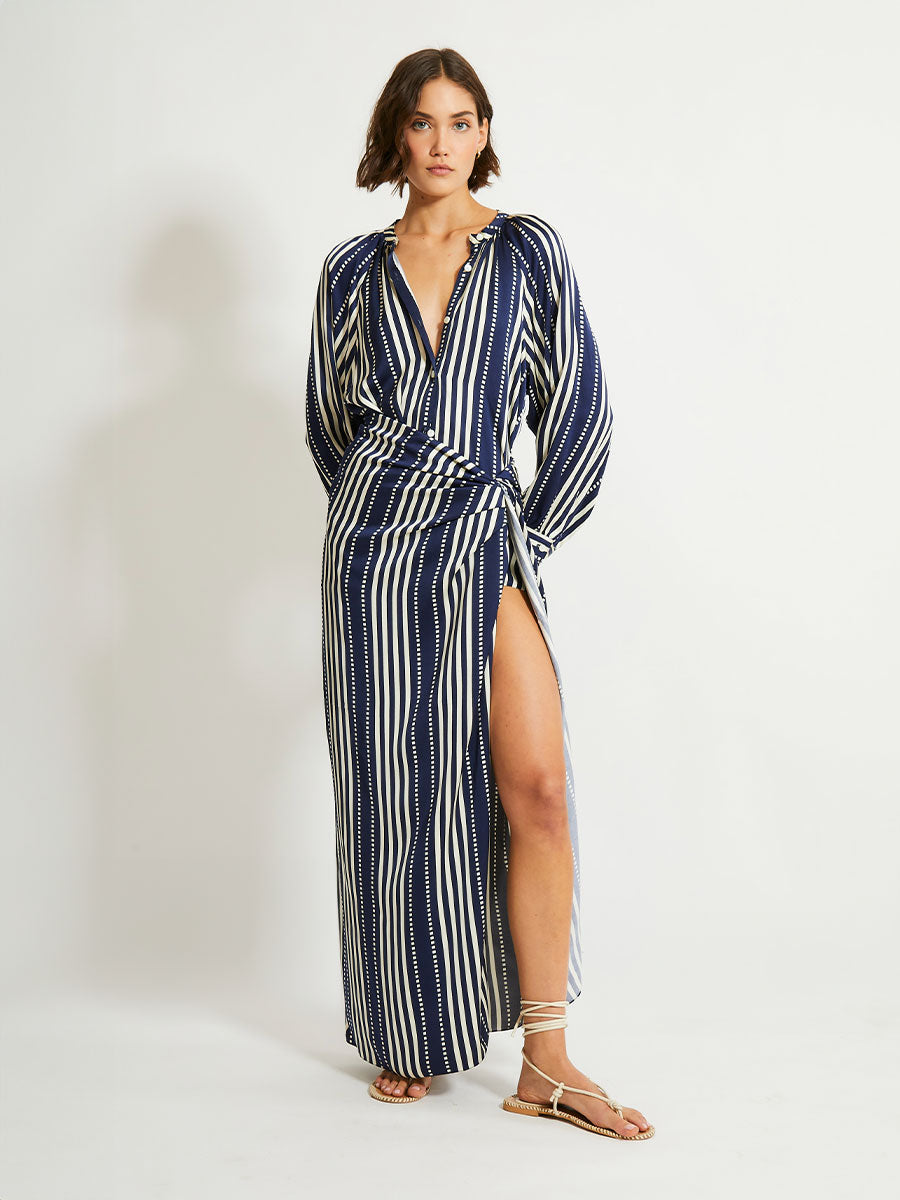 Woman Standing Wearing lemlem ADIA Sarong featuring a classic navy background with ivory stripes and dots on a silky fabric and a matching blouse