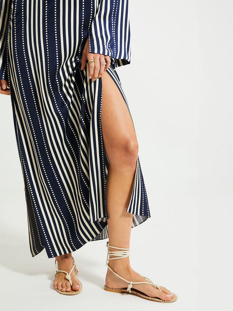 Close up on Woman's legs Standing Wearing lemlem Theodora dress featuring a classic navy background with ivory stripes and dots