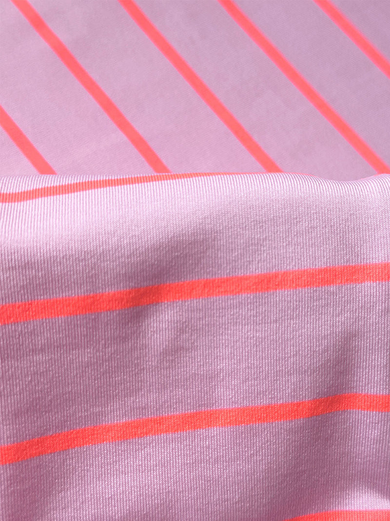 Close up on lemlem Jeliba Pink Fabric featuring soft pink color accented by neon orange red stripes creating unique and striking pieces and matching high waist bottom