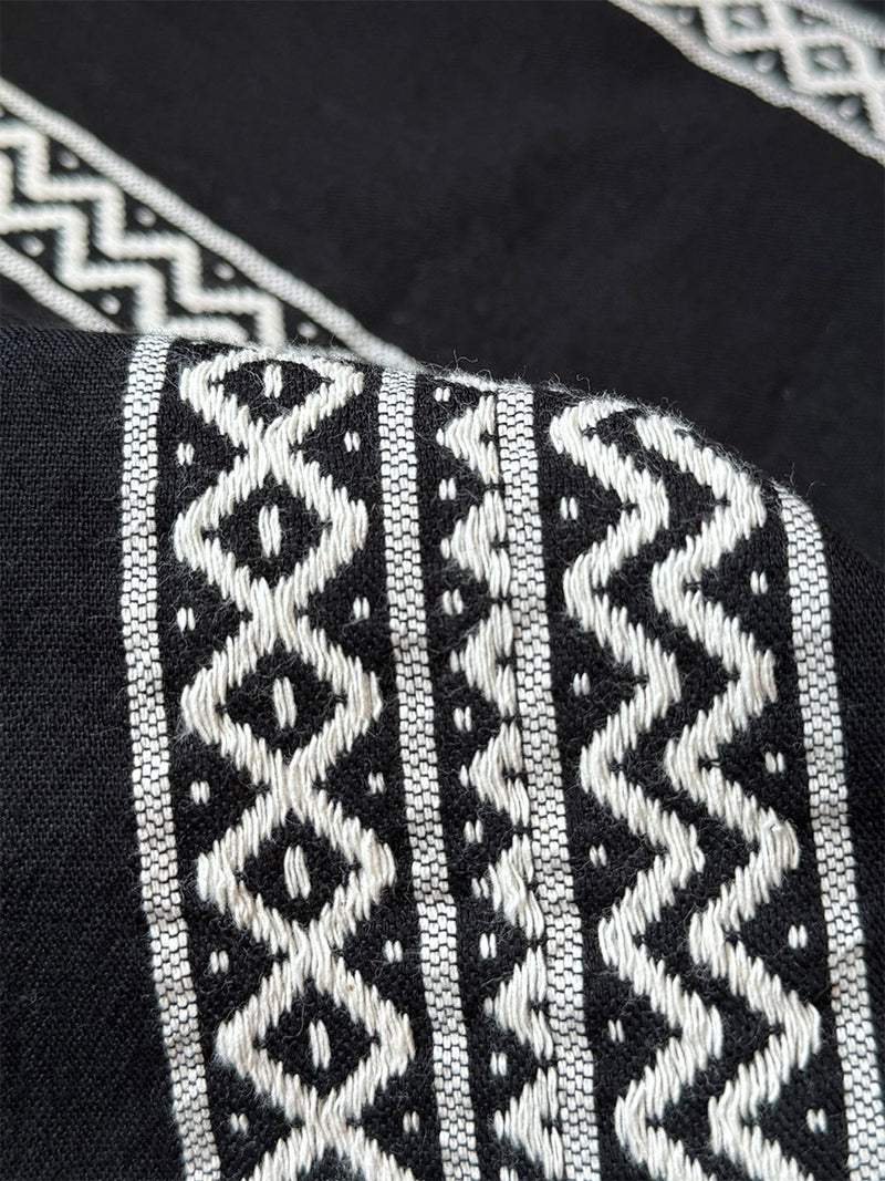 close up on a lemlem lulit black fabric  Featuring rich black background with intricate cream Tibeb border pattern