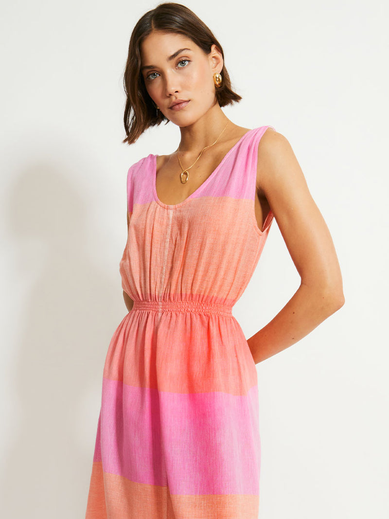 Woman Standing Wearing lemlem Melat Scoop Dress featuring gauzy fabric with a beautiful ombre color block of pink, blush, and peach colors.